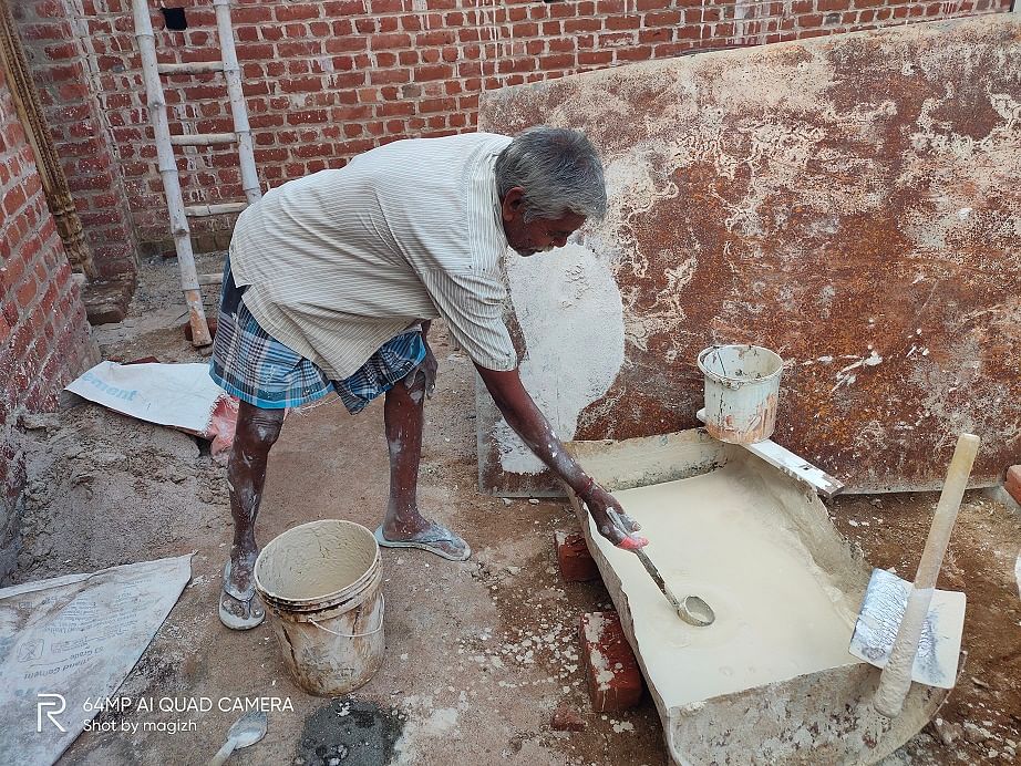 An old mason plasters the wall using lime in different layers